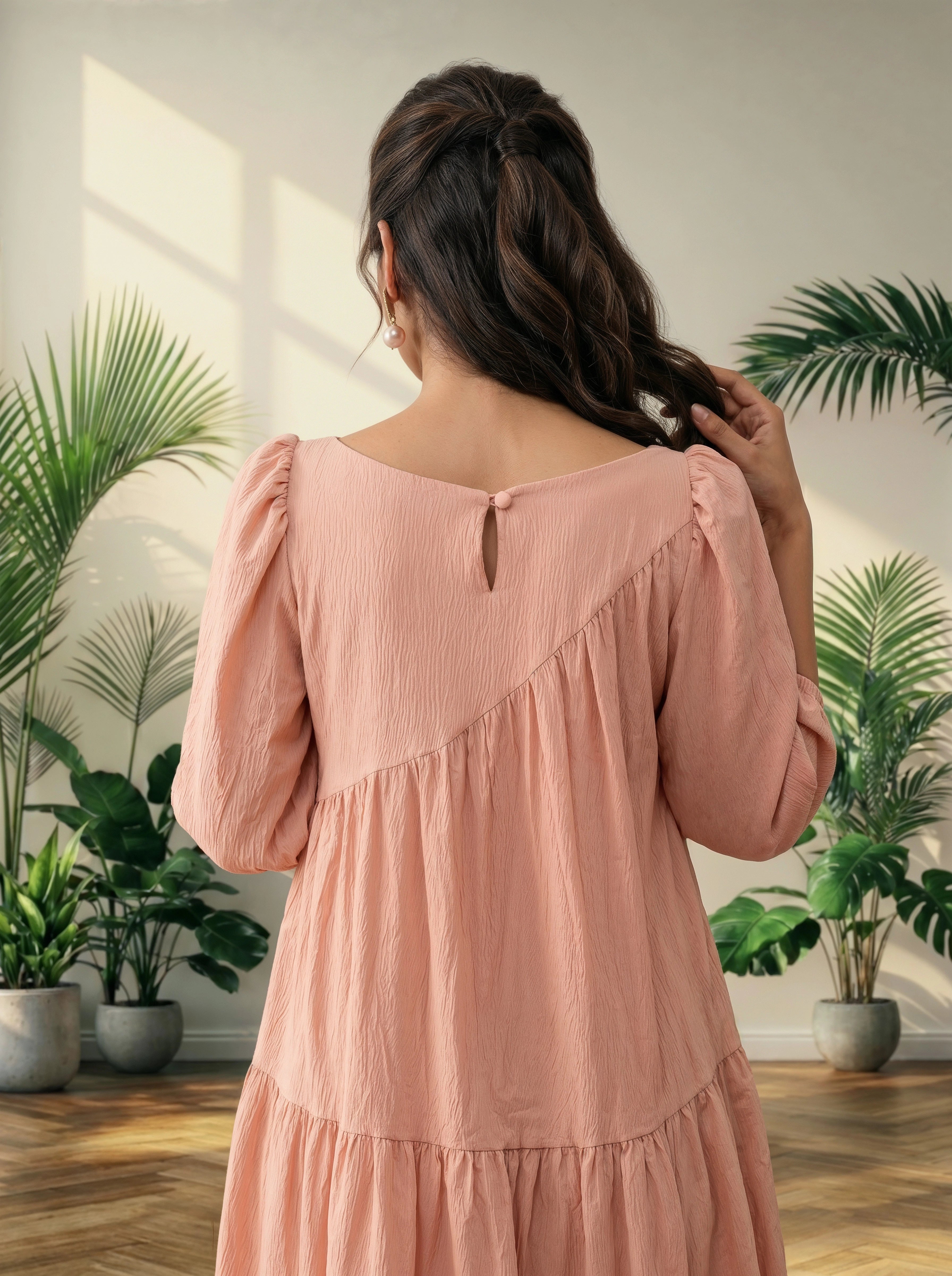 Woman in a pink dress standing in a room with plants