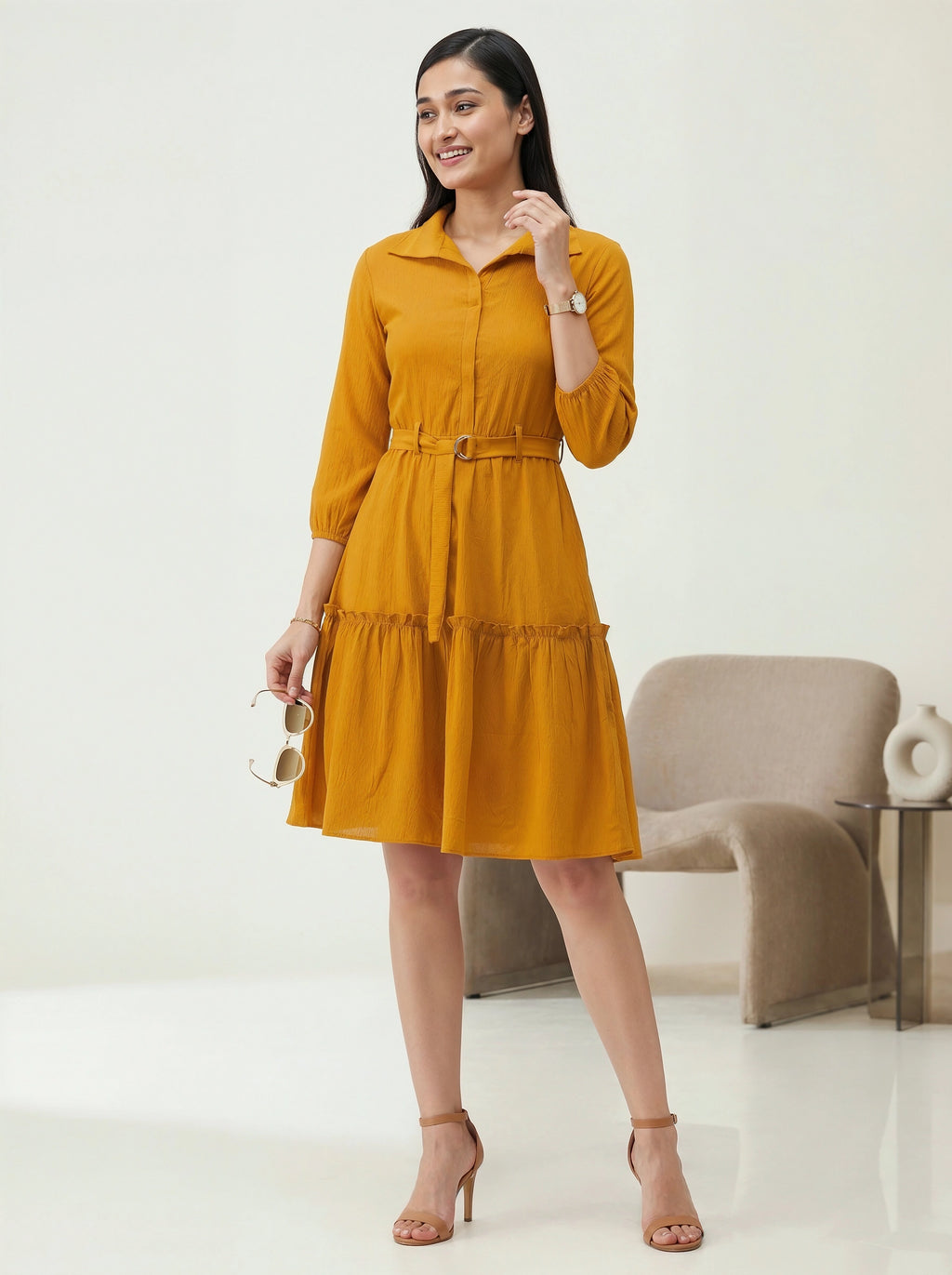 Woman wearing a mustard yellow dress standing in a minimalistic room.