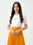 Woman wearing a white top with gold accents and a yellow pleated skirt on a white background