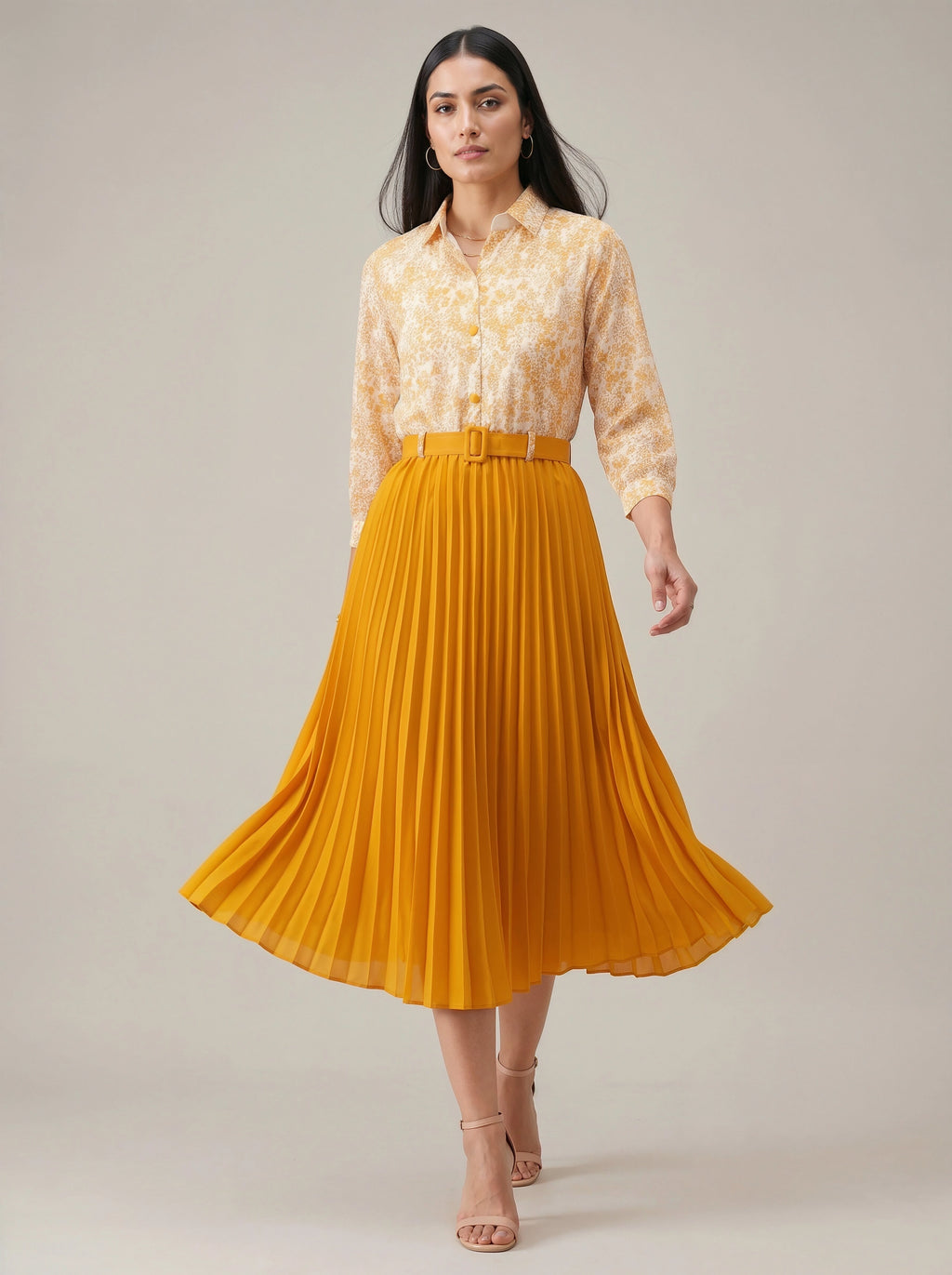Woman wearing a yellow pleated skirt and patterned blouse on a plain background