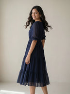 Woman wearing a navy blue dress against a plain background
