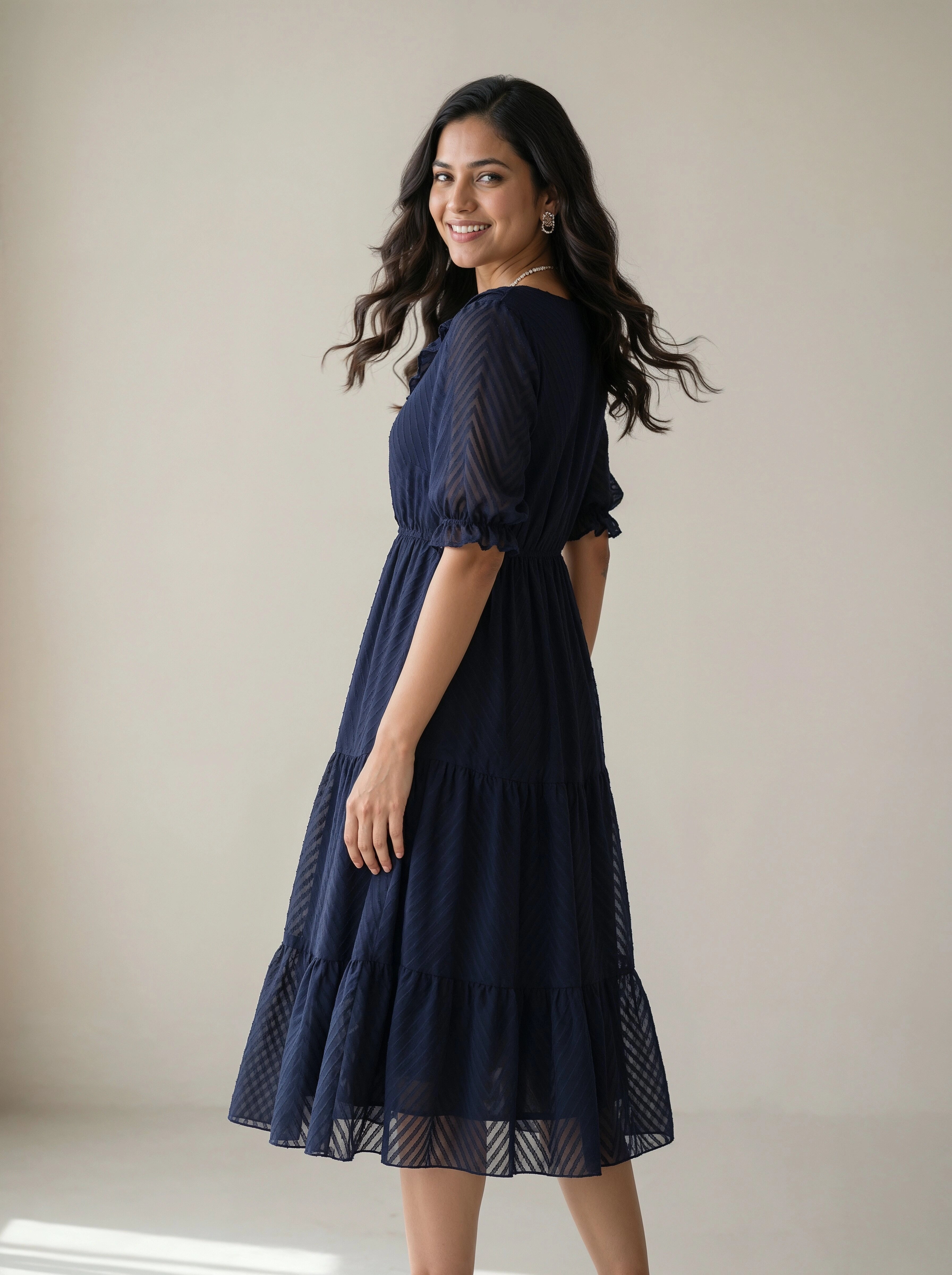 Woman wearing a navy blue dress against a plain background