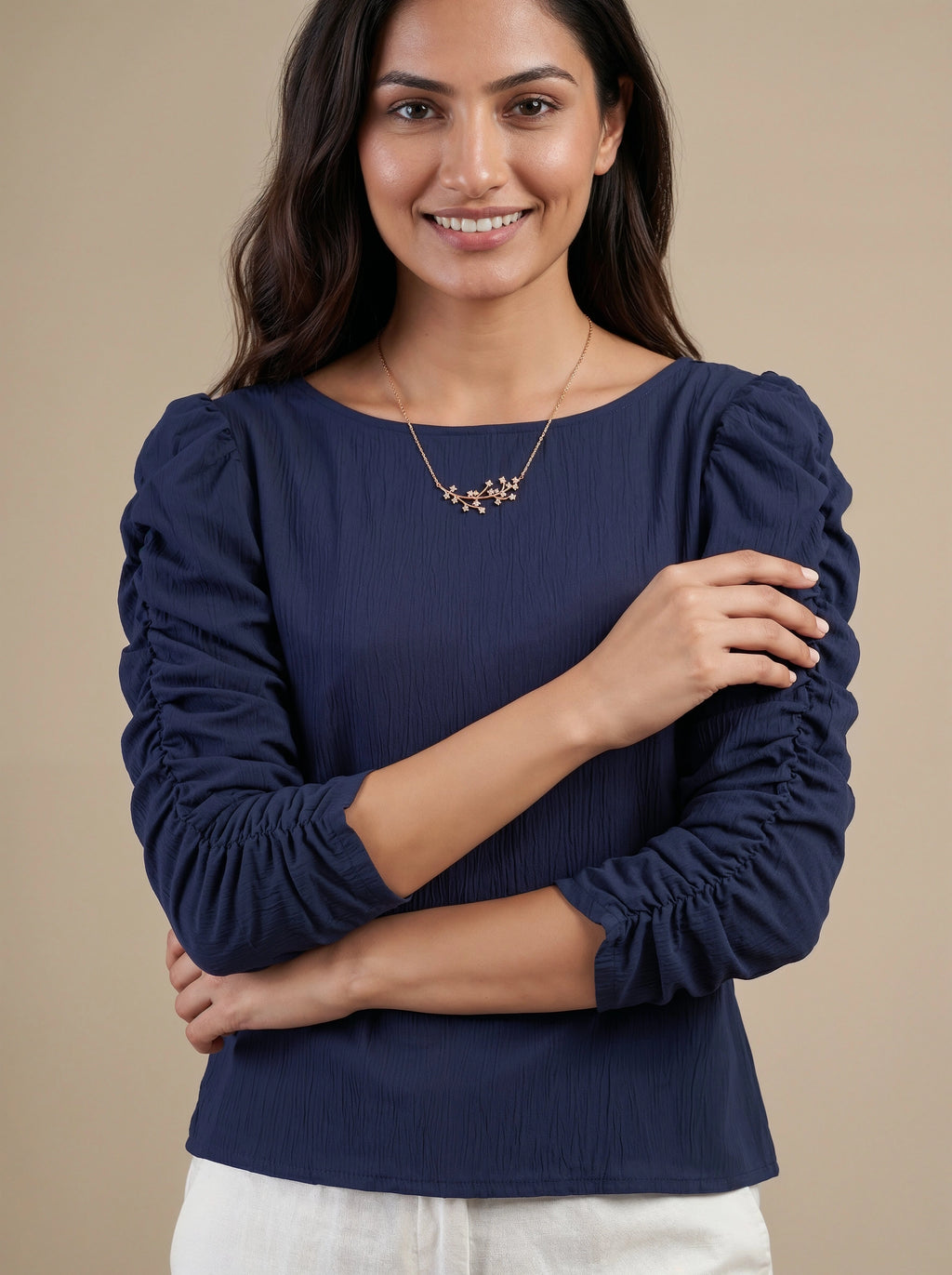 Woman wearing a navy blue blouse with ruffled sleeves on a beige background