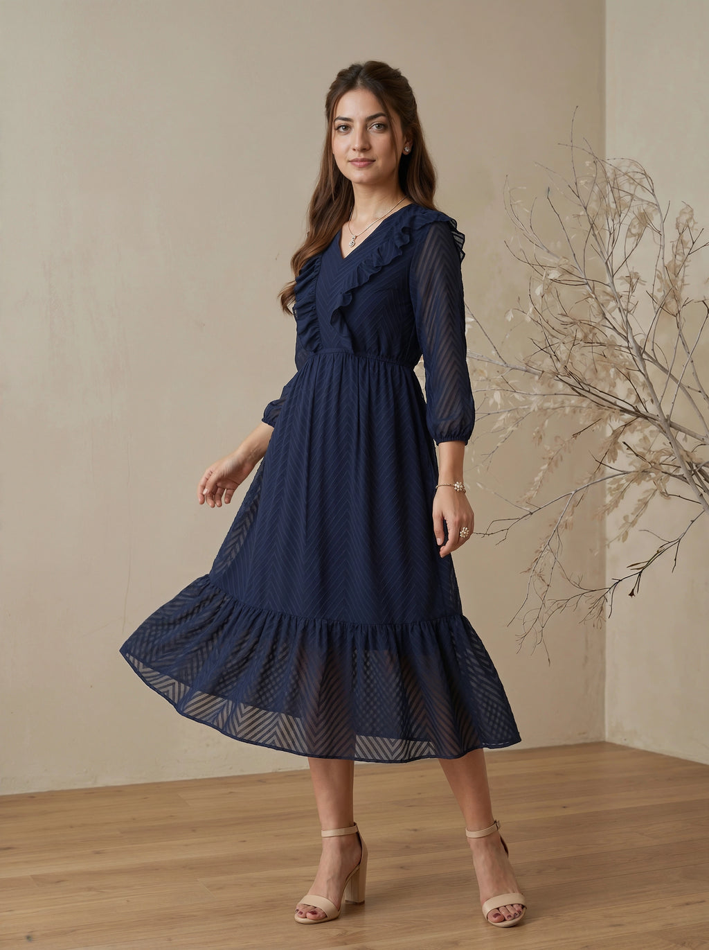Woman wearing a navy blue dress standing in a room with a neutral background