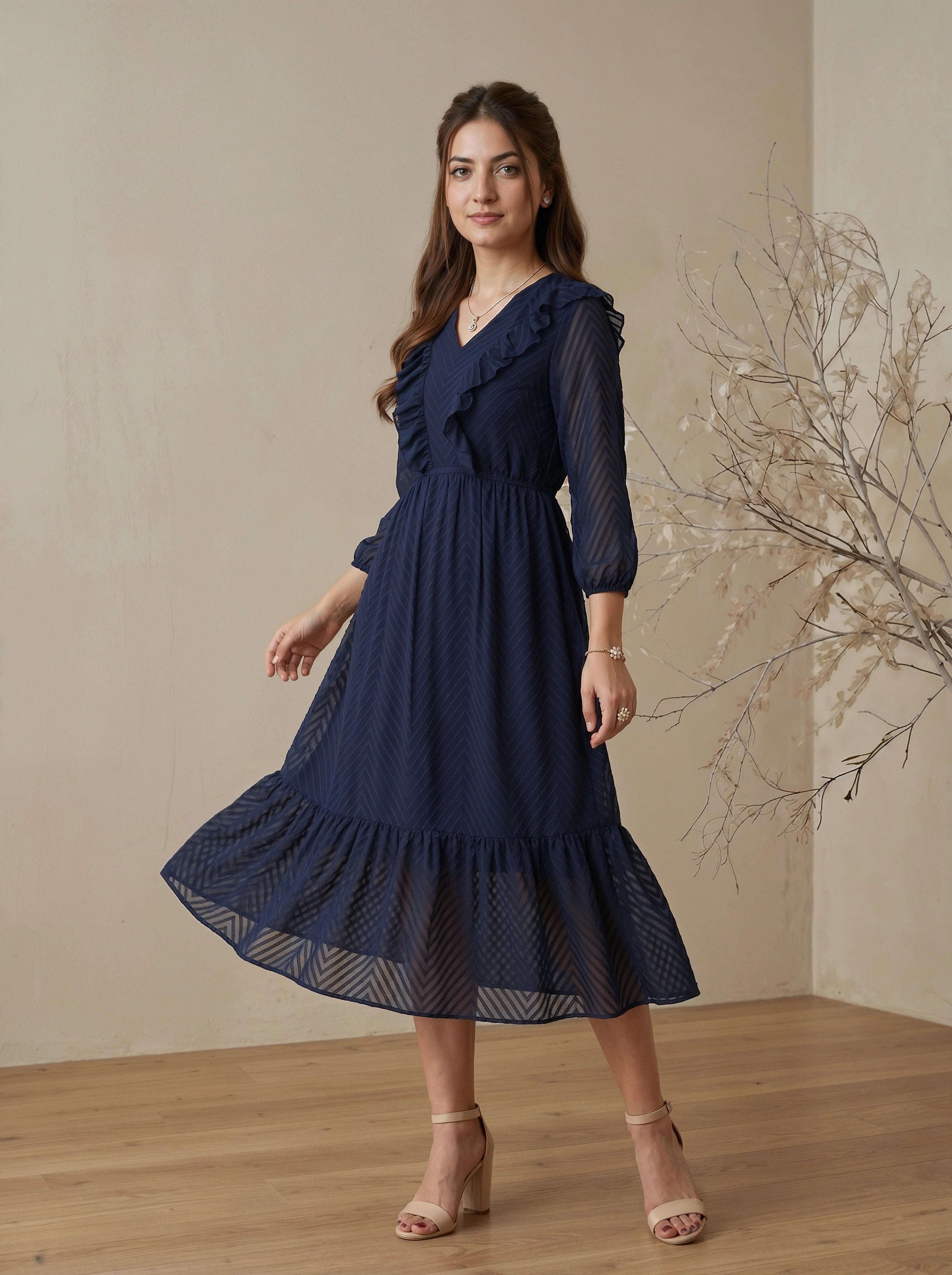 Woman wearing a navy blue dress standing in a room with a neutral background