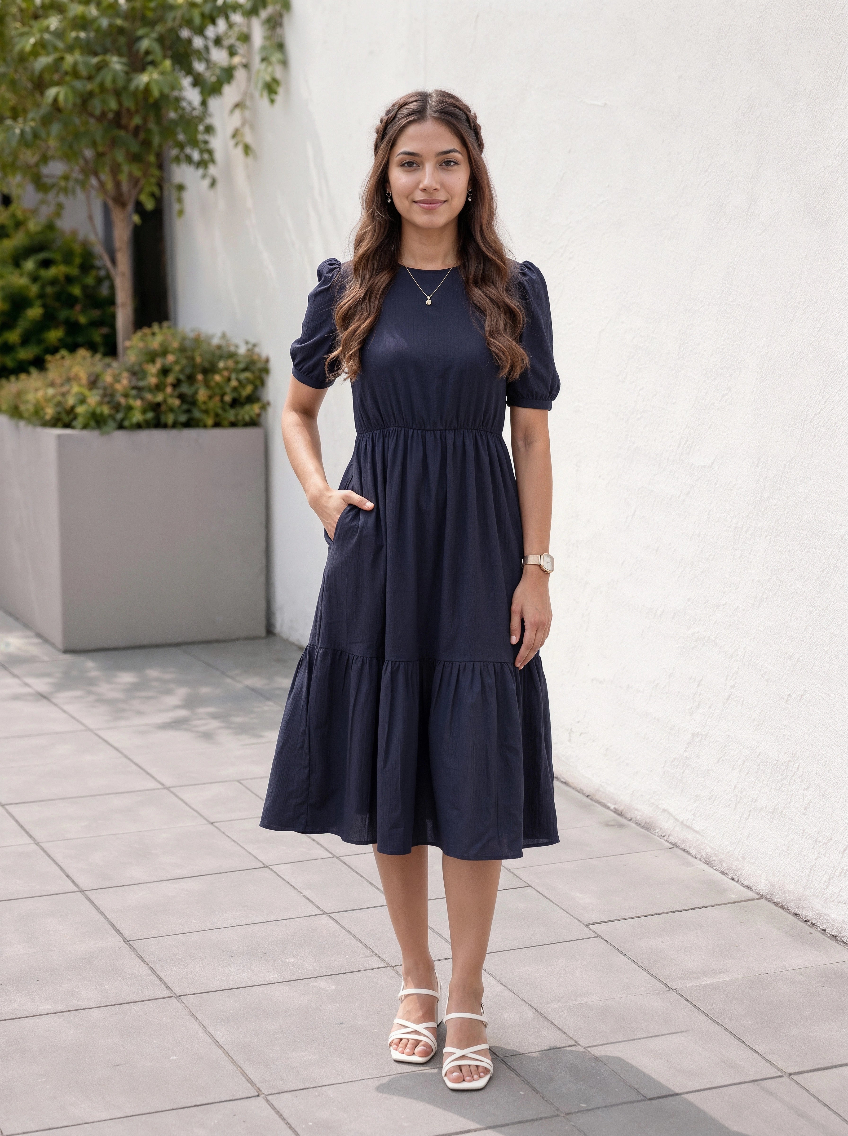 Woman wearing a navy blue dress standing outdoors on a tiled pavement.