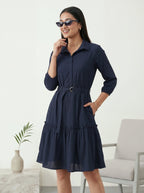Woman wearing a navy blue dress in a minimal indoor setting