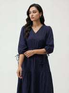 Woman wearing a navy blue dress with a plain background