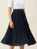 Navy pleated skirt worn with a white top on a beige background