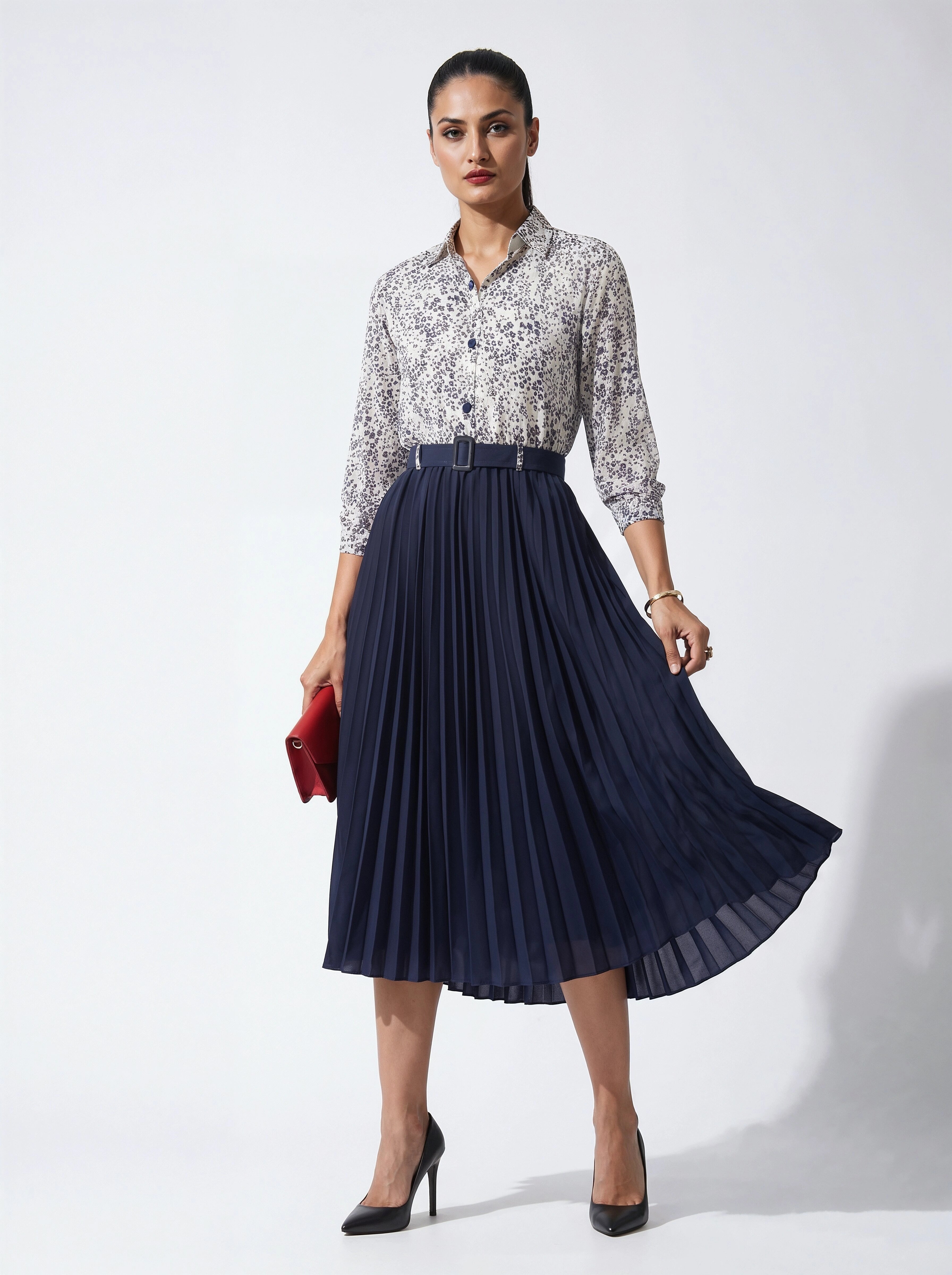 Woman wearing a floral blouse and navy pleated skirt on a white background