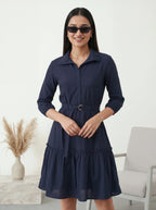 Woman wearing a navy blue dress with sunglasses indoors