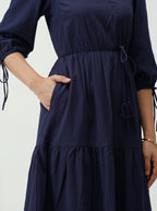 Navy blue dress with tiered skirt and drawstring details on a white background