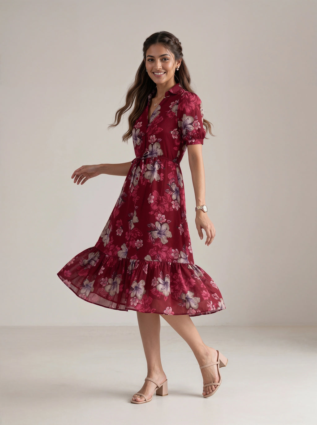 A woman modeling a short-sleeve midi dress with a ruffled hem in a deep red floral print, paired with beige heeled sandals, against a neutral studio backdrop.