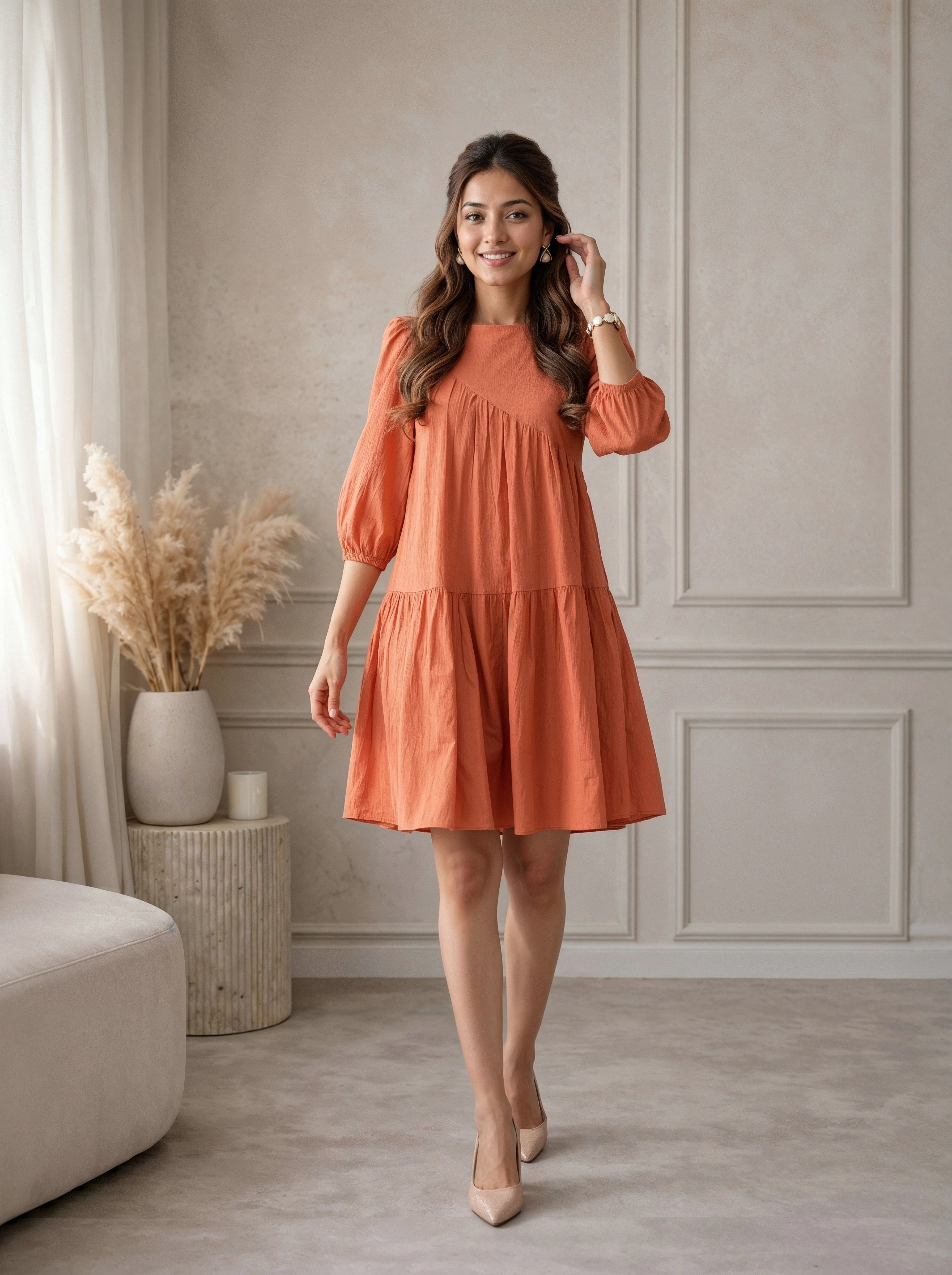 Woman wearing an orange dress standing in a room with neutral decor.