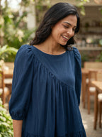 Woman wearing a blue dress standing outdoors with blurred background