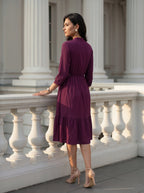 Woman in a purple dress standing on a stone staircase with classical architecture in the background