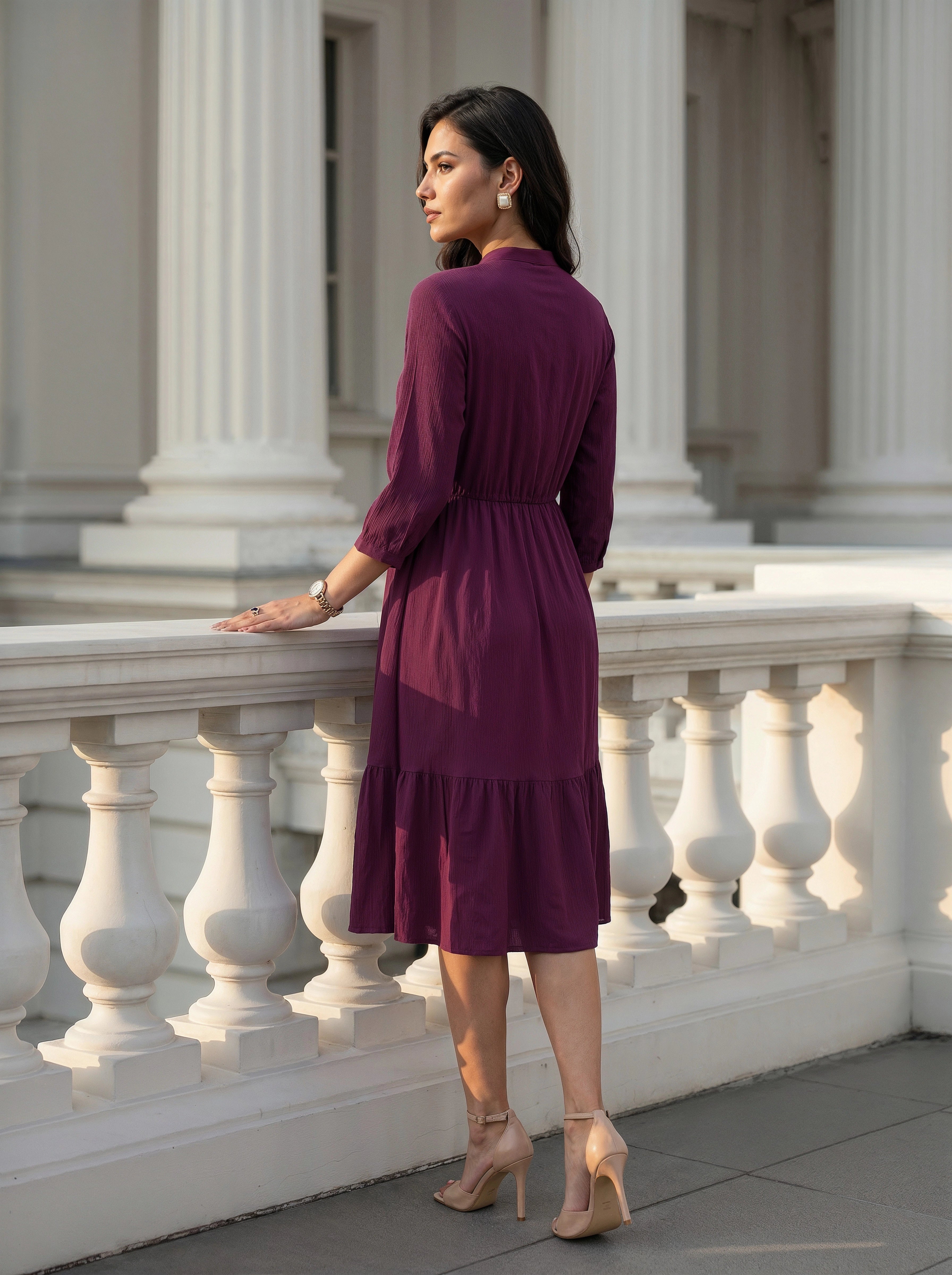 Woman in a purple dress standing on a stone staircase with classical architecture in the background