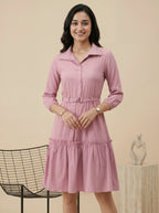 Woman wearing a pink dress standing against a beige background