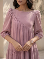 Woman wearing a pink dress with long sleeves against a neutral background