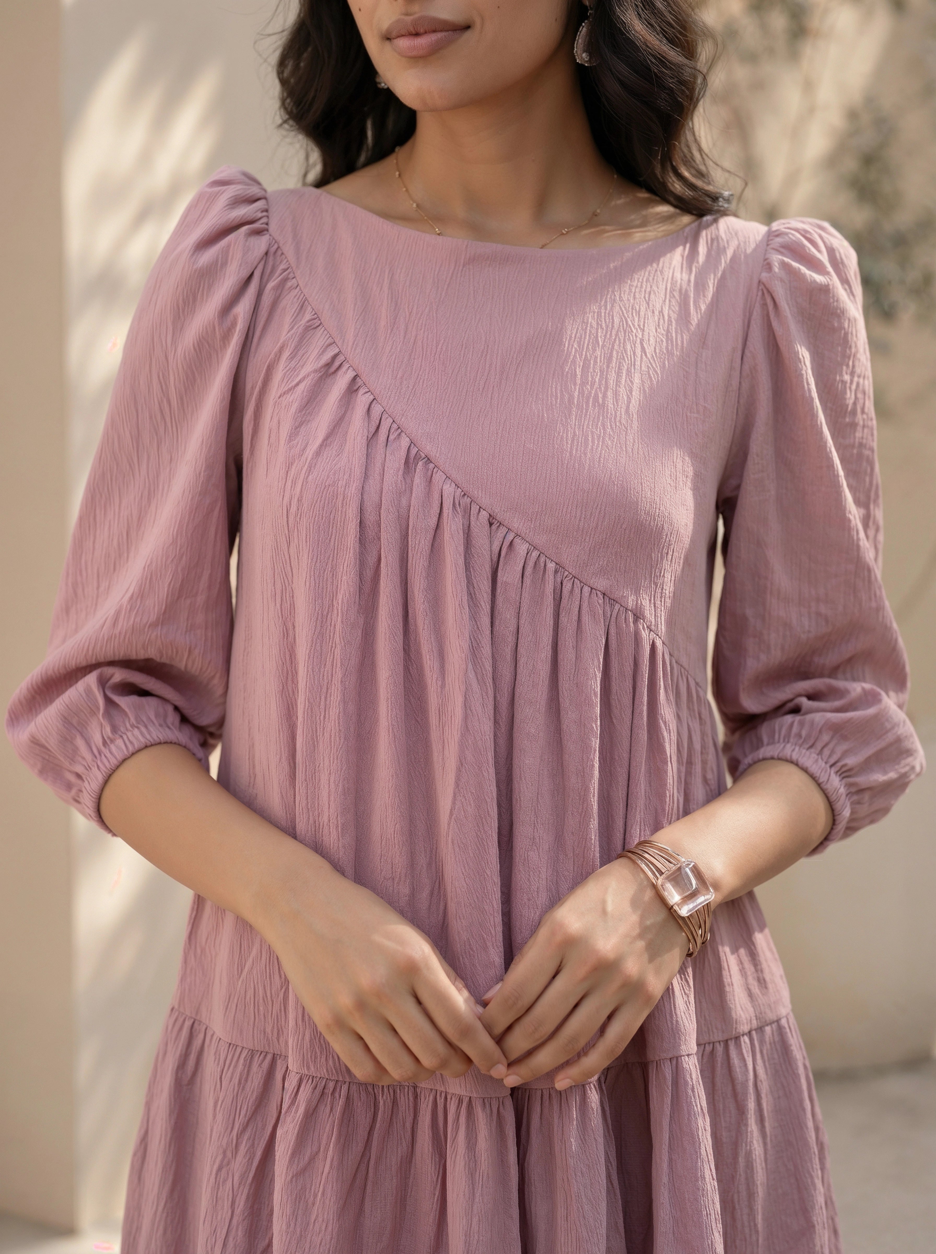Woman wearing a pink dress with long sleeves against a neutral background