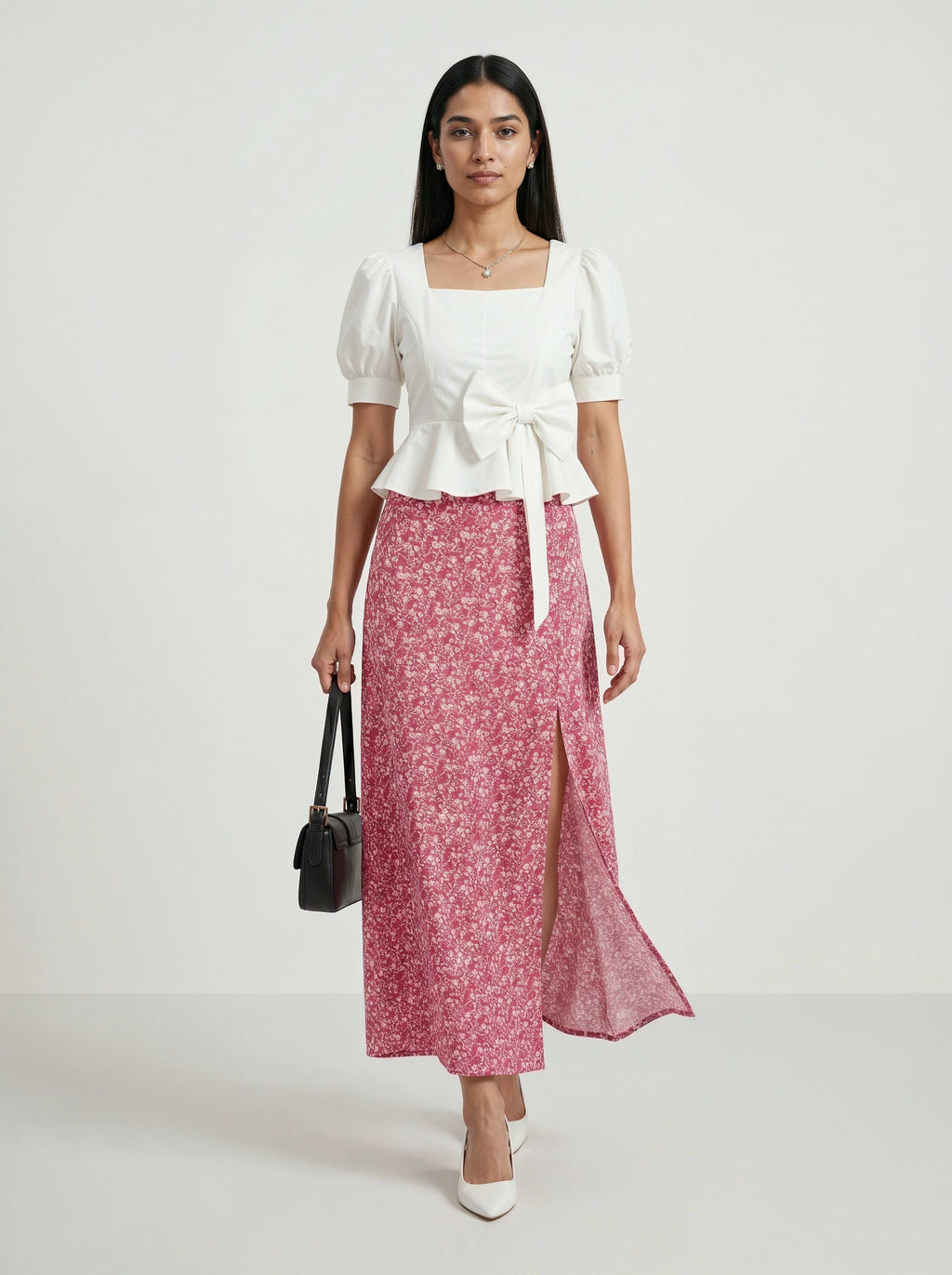 Woman wearing a white top and pink floral skirt on a white background