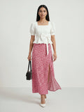 Woman wearing a white top and pink floral skirt on a white background