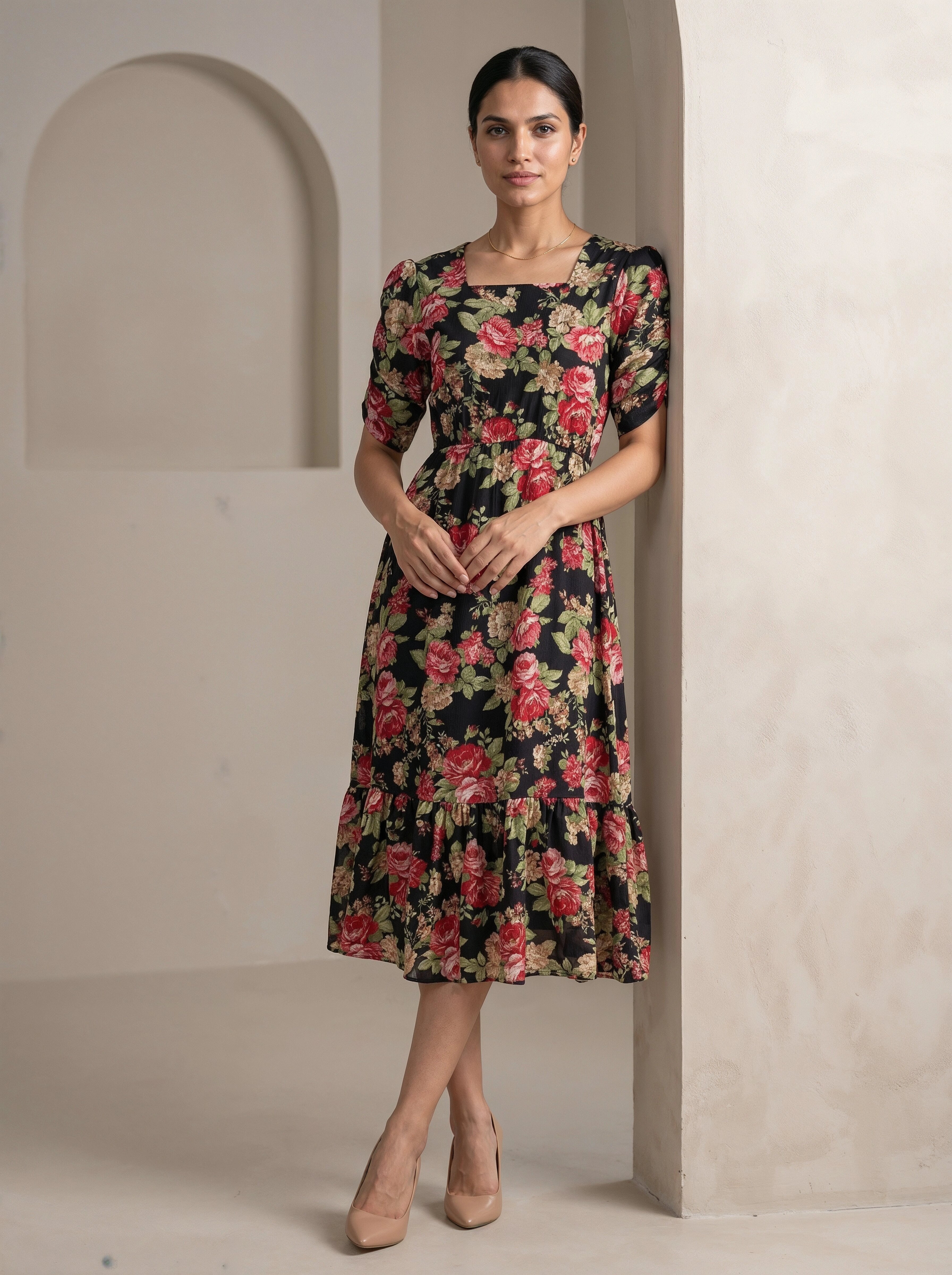 Woman wearing a Pink floral dress standing against a neutral wall.