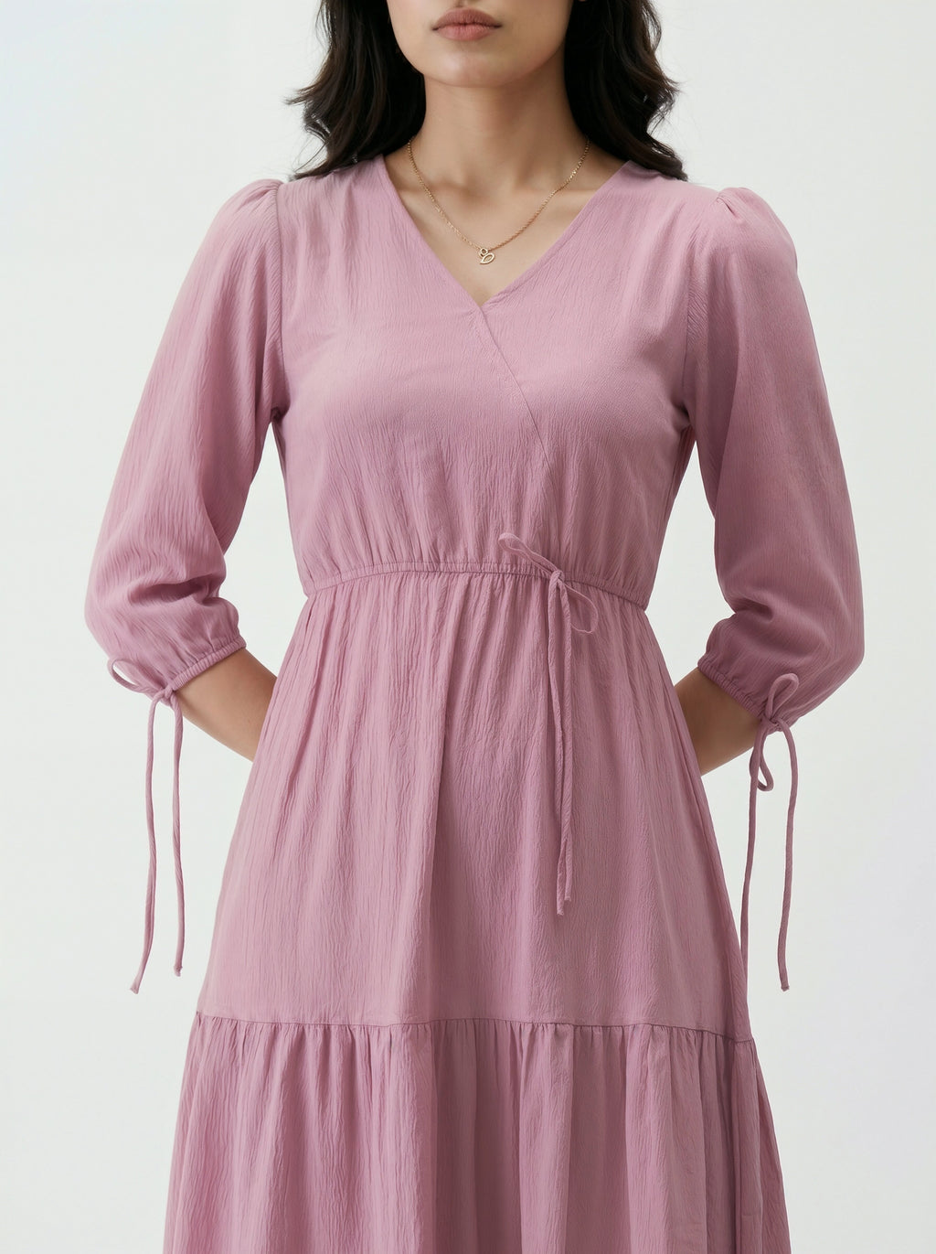 Pink dress with long sleeves worn by a person on a white background