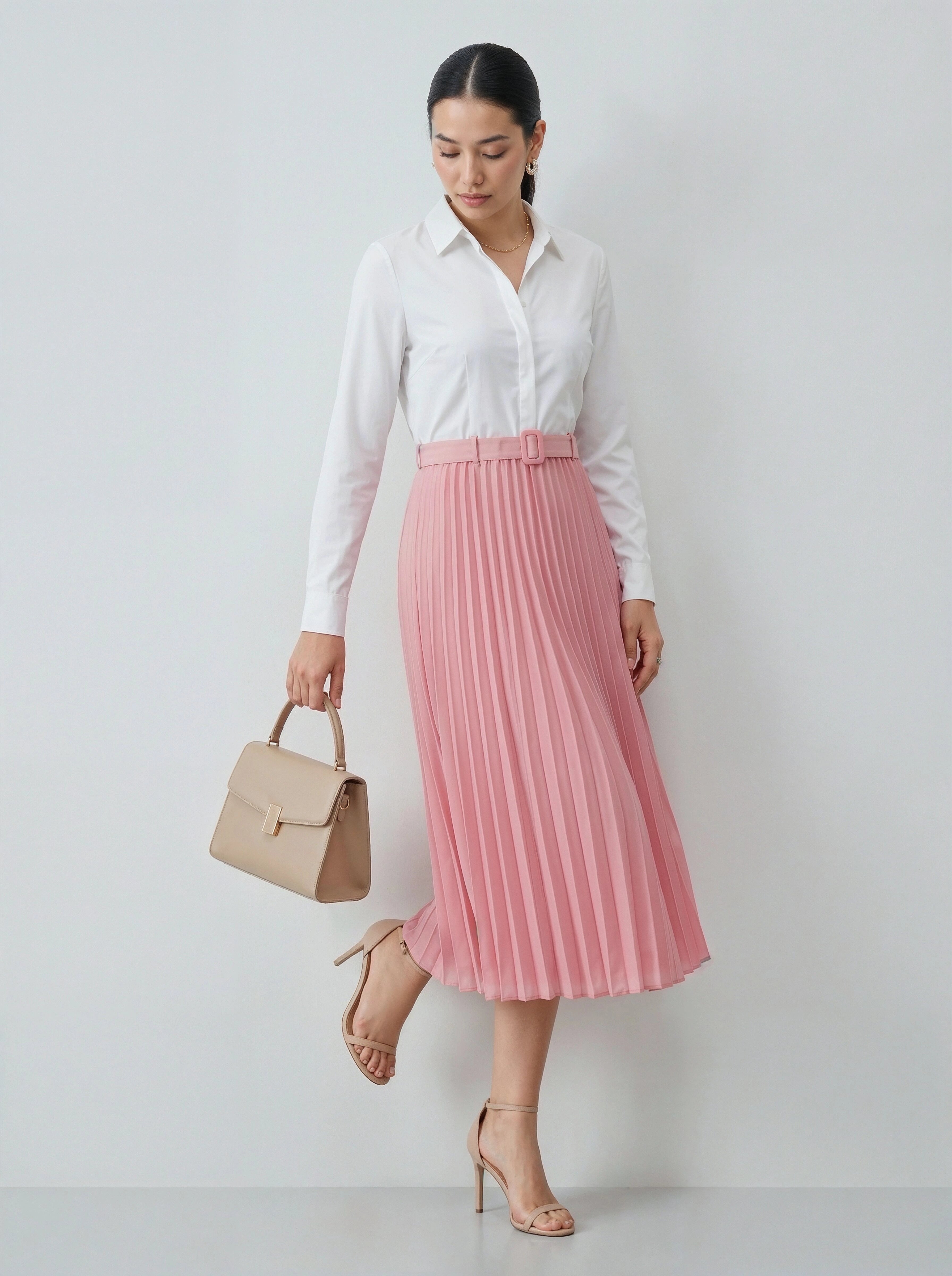 Woman wearing a white blouse and pink pleated skirt with a beige handbag on a light gray background