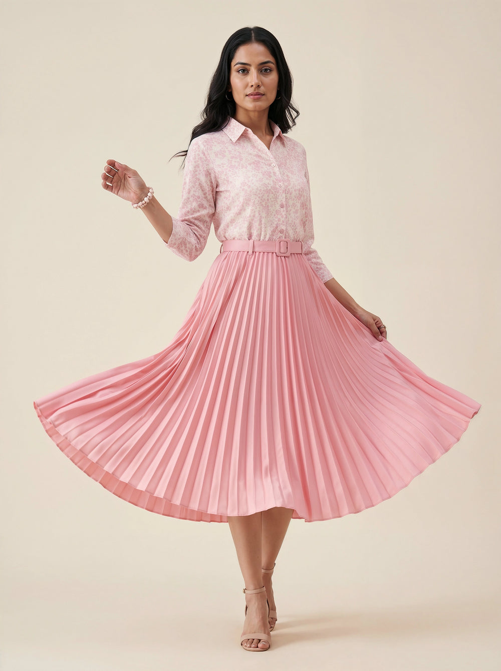 Woman wearing a pink pleated skirt and light pink shirt on a beige background