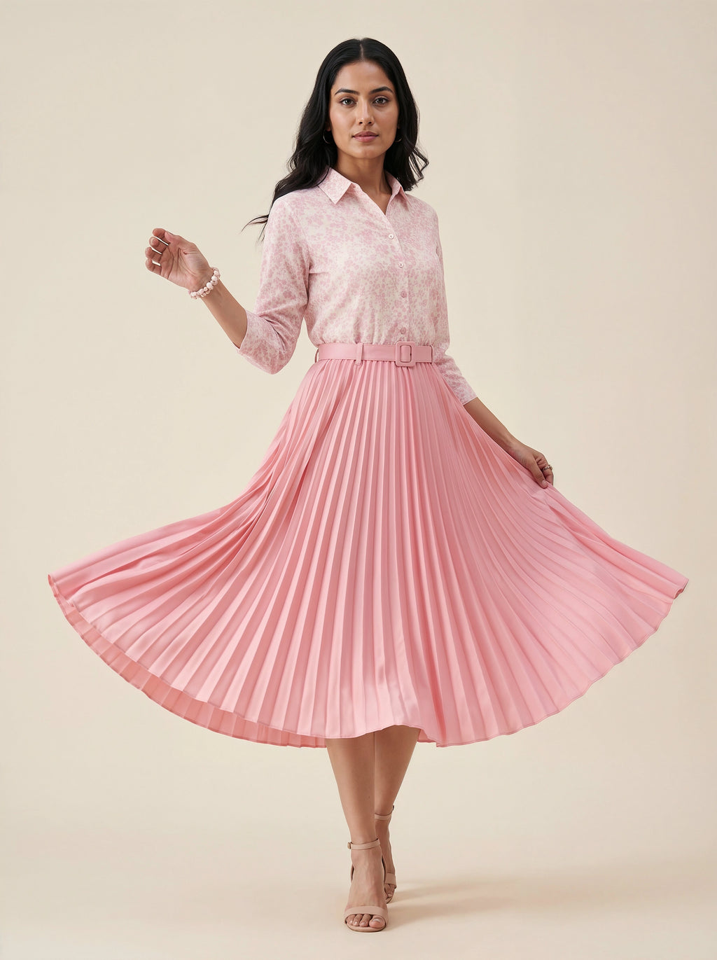 Woman wearing a pink pleated skirt and light pink shirt on a beige background