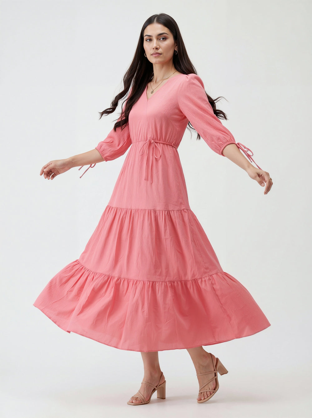 Woman wearing a pink dress with tiered skirt on a white background