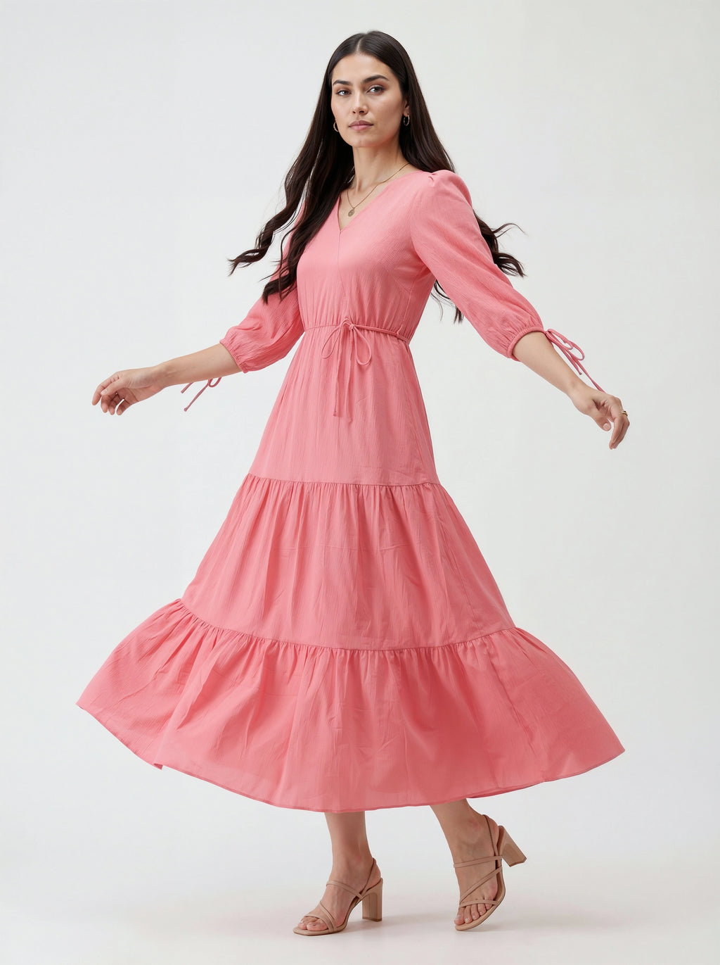 Woman wearing a pink dress with tiered skirt on a white background