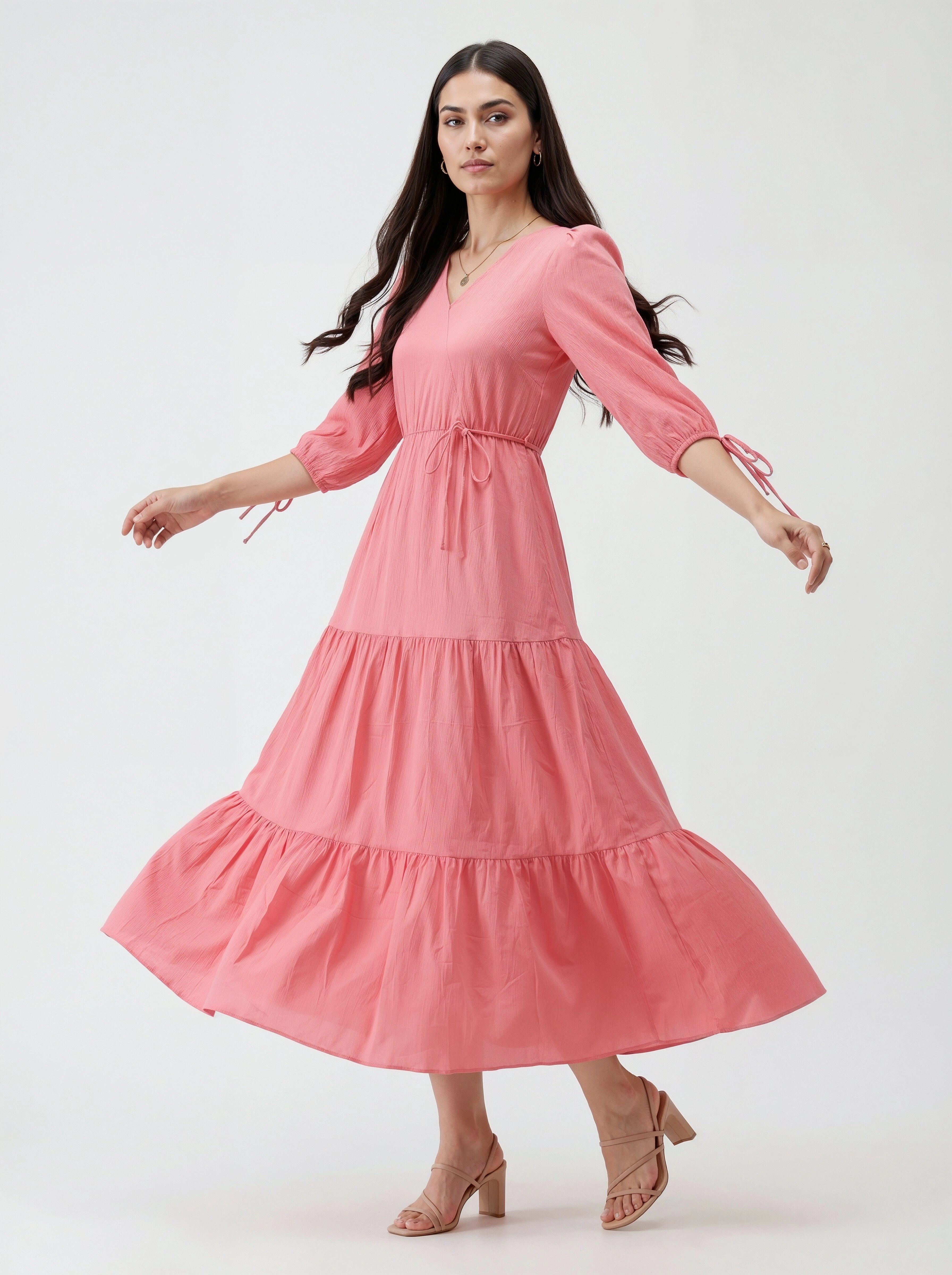 Woman wearing a pink dress with tiered skirt on a white background