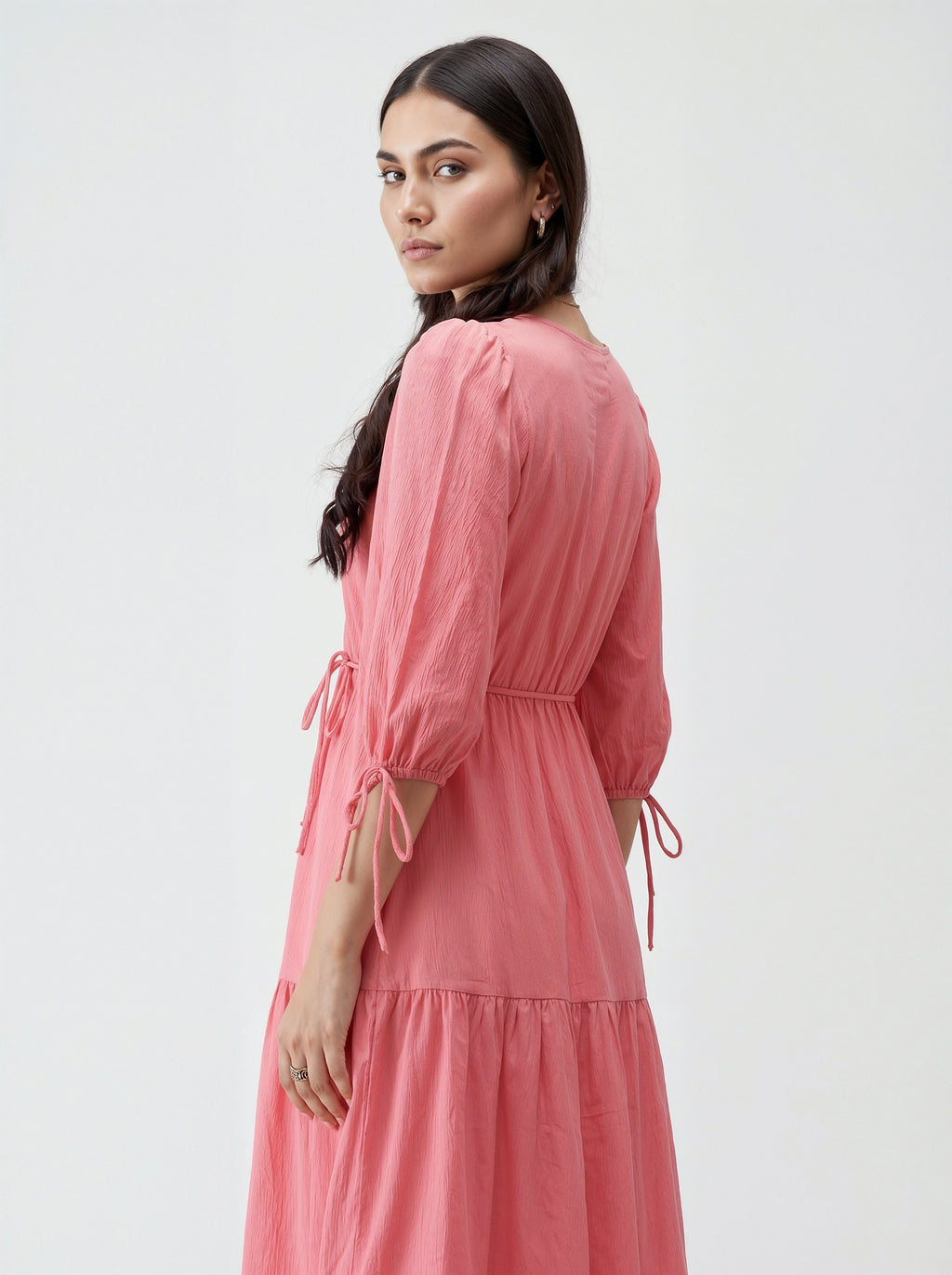 Woman wearing a pink dress with long sleeves and a white background