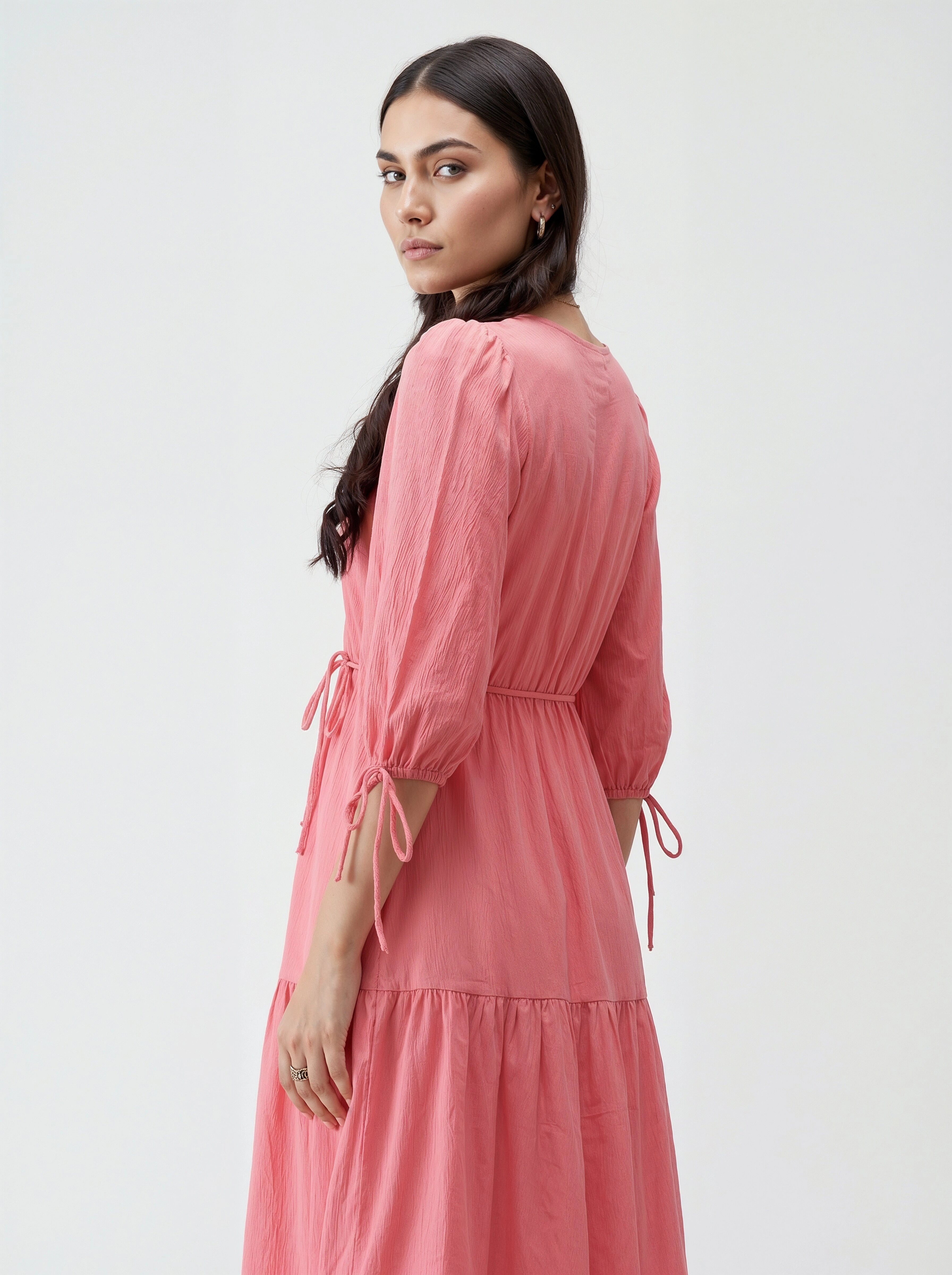 Woman wearing a pink dress with long sleeves and a white background