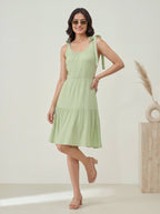 Woman wearing a light green dress standing against a white background