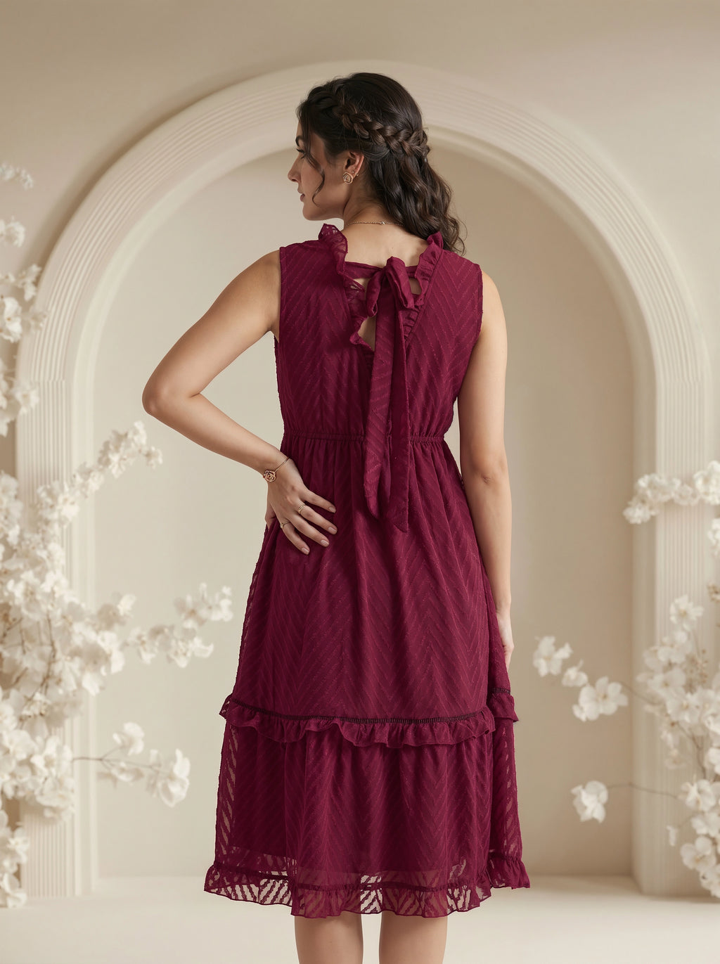 Woman wearing a burgundy dress with floral decorations in an elegant indoor setting.