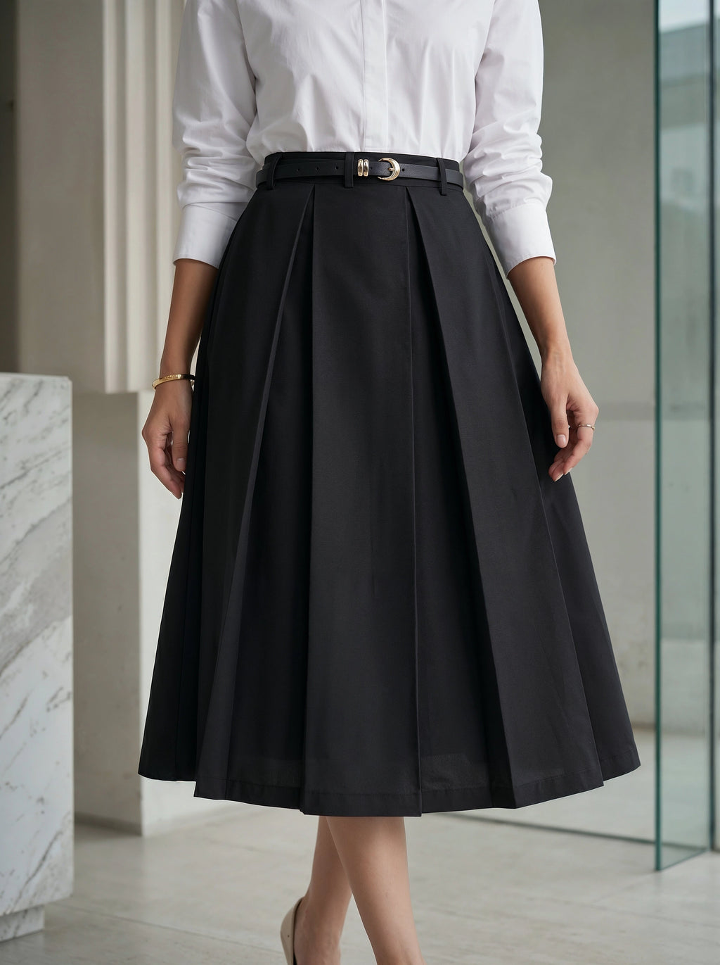 Person wearing a black skirt and white shirt in an indoor setting