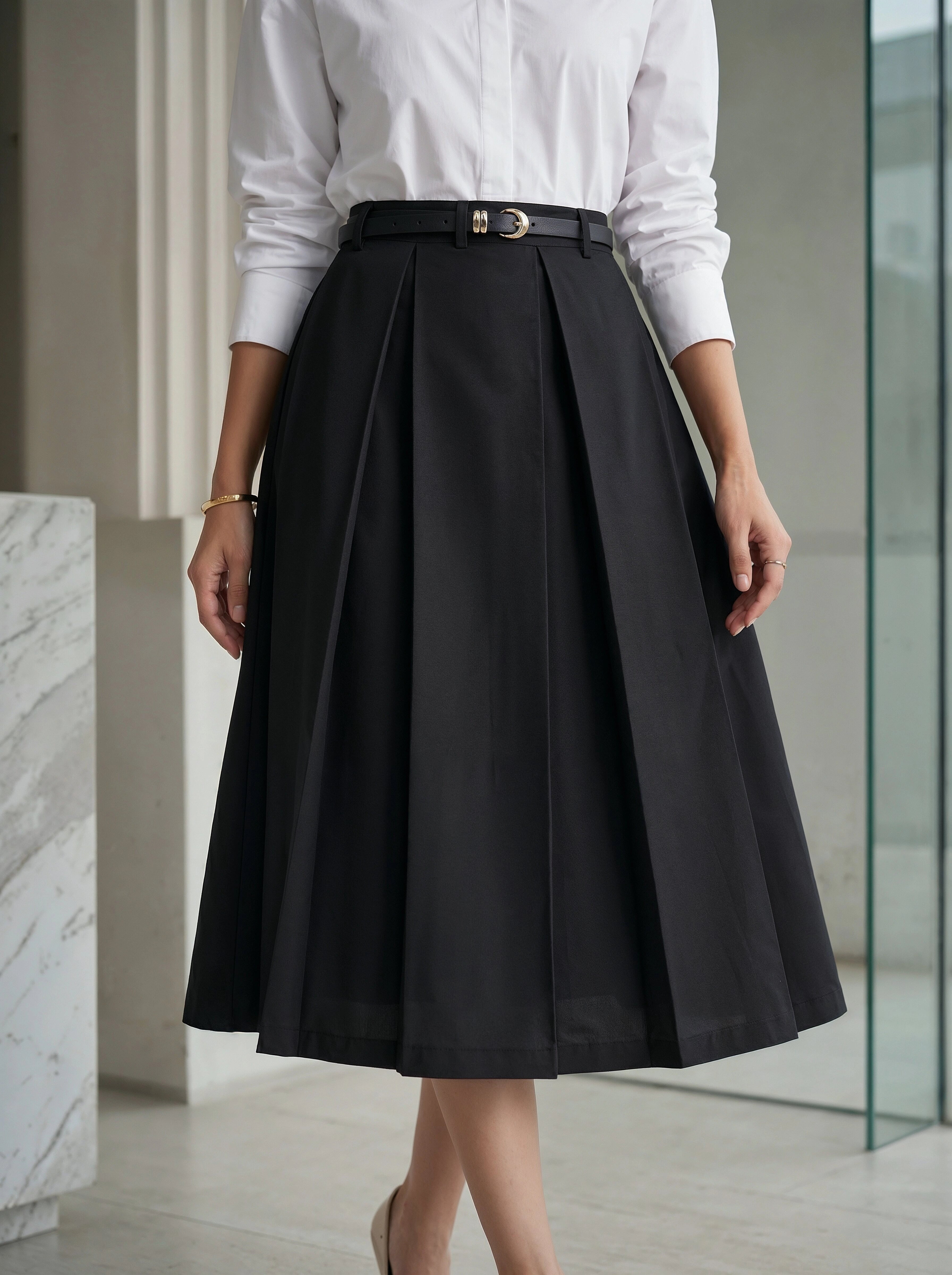 Person wearing a black skirt and white shirt in an indoor setting