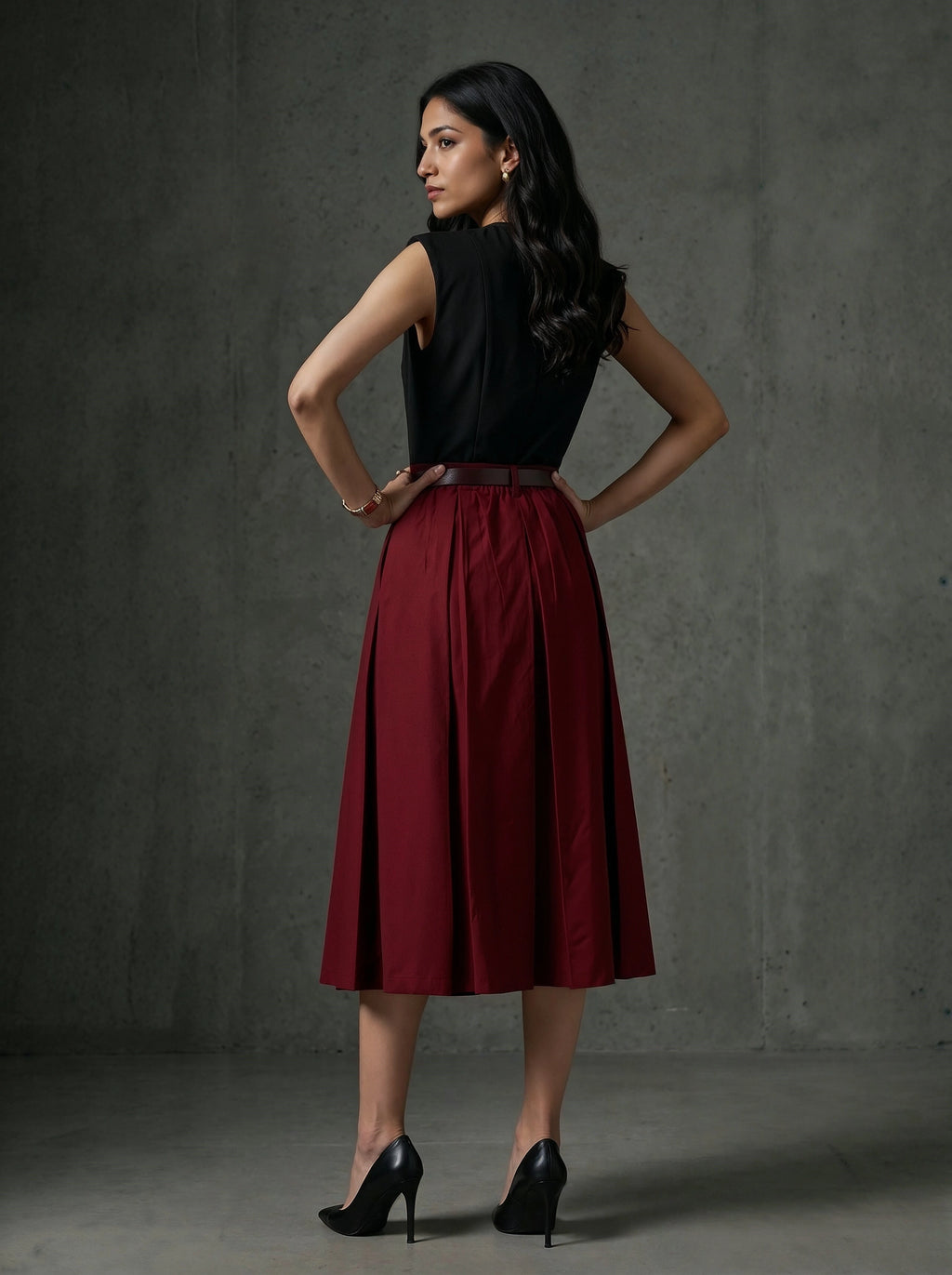 Woman wearing a black top and red skirt against a gray background