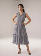Woman wearing a sleeveless, patterned dress against a plain background