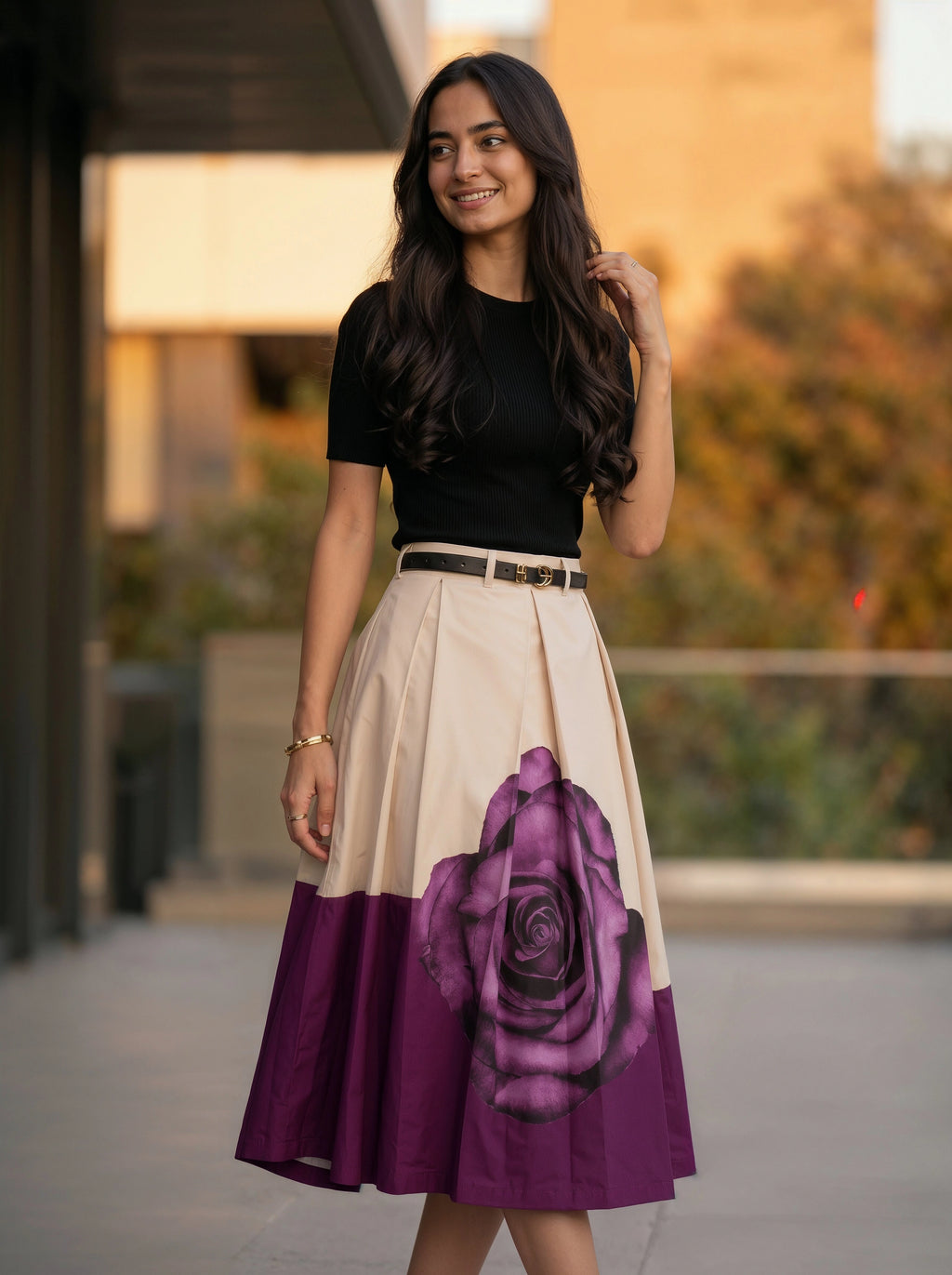 Woman wearing a black top and a two-tone skirt with a purple rose design outdoors.