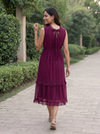 Woman in a purple dress walking on a paved path with greenery in the background