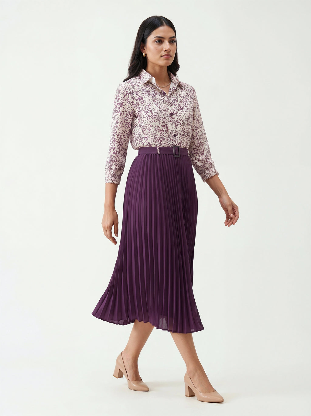 Woman wearing a floral blouse and purple pleated skirt on a white background