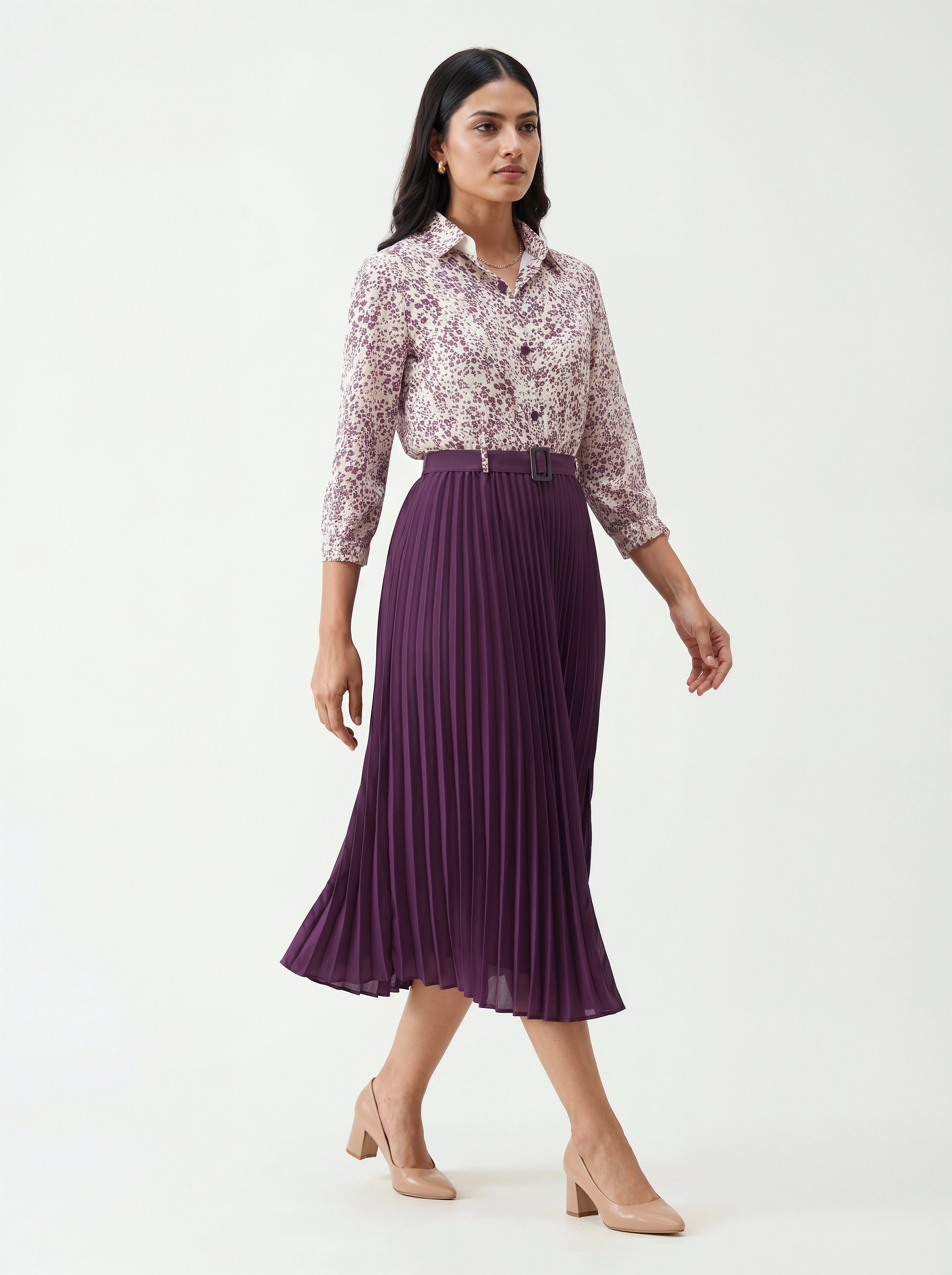Woman wearing a floral blouse and purple pleated skirt on a white background