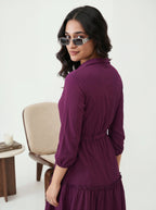 Woman wearing a purple dress and sunglasses in a minimal indoor setting