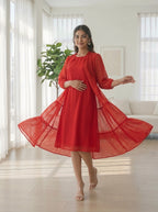 Woman in a red dress standing in a bright room with large windows.