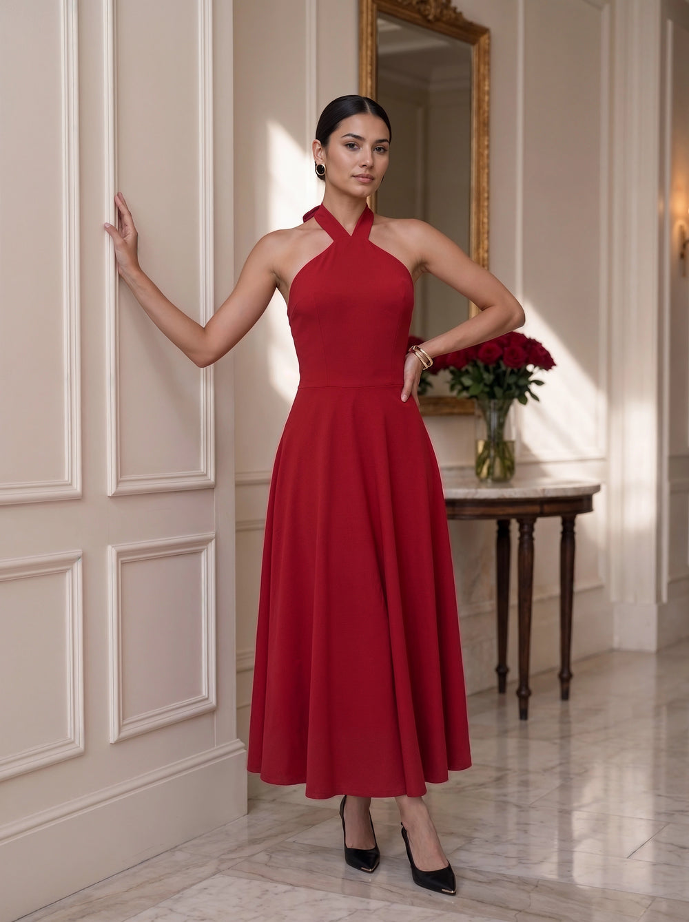 A woman viewed from behind wearing a sage green tiered dress with puff sleeves and a keyhole back detail, styled with a white bow in her hair in a warm, decorated indoor setting.