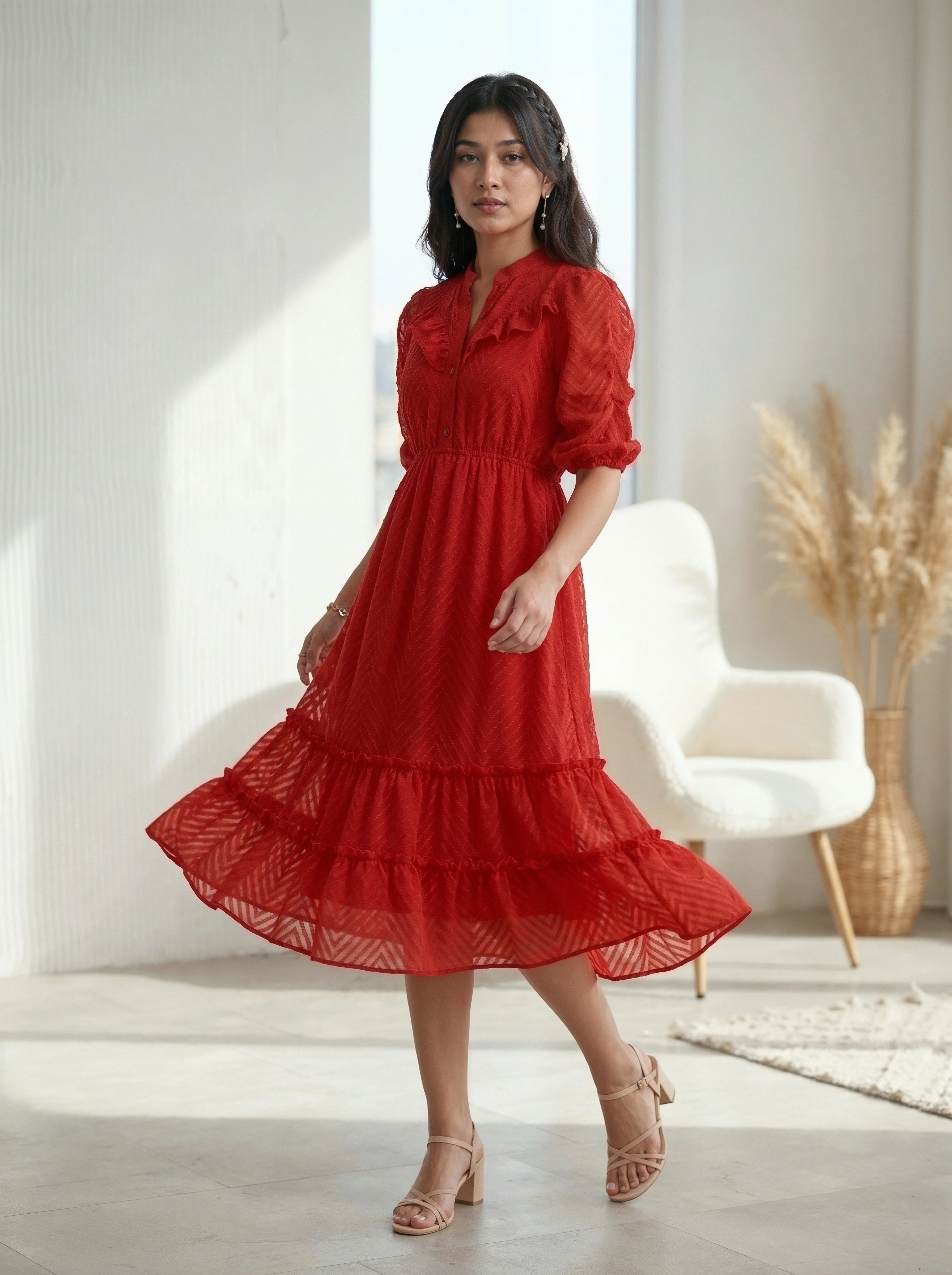 Woman wearing a navy blue dress with ruffled sleeves against a beige wall.